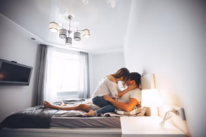 Állüképeeség az ágyban címú blog bejegyzéshez képi illusztráció. A fotón egy szoba látható, a közepén egy ágy, mindent a fehér szín ural. Az ágyon pedig a fiatal párt láthatunk, a férfi a hátát a falnak támasztja, a nő pedig a férfi comján, vele szemben ül és a fejük összeér.